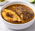 Bowl of fish pepper soup with a lime wedge on a white plate