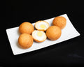 Five golden-brown fried bread balls, with two cut open to show a soft-boiled egg inside, served on a white rectangular plate against a solid black background.