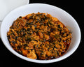  a small white bowl of spicy vegetable sauce, set against a solid black background.
