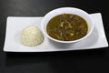 ball of white rice on a plate, next to it is a bowl of green broth