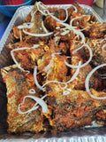 Fried fish with tomato sauce and onions on a metal tray